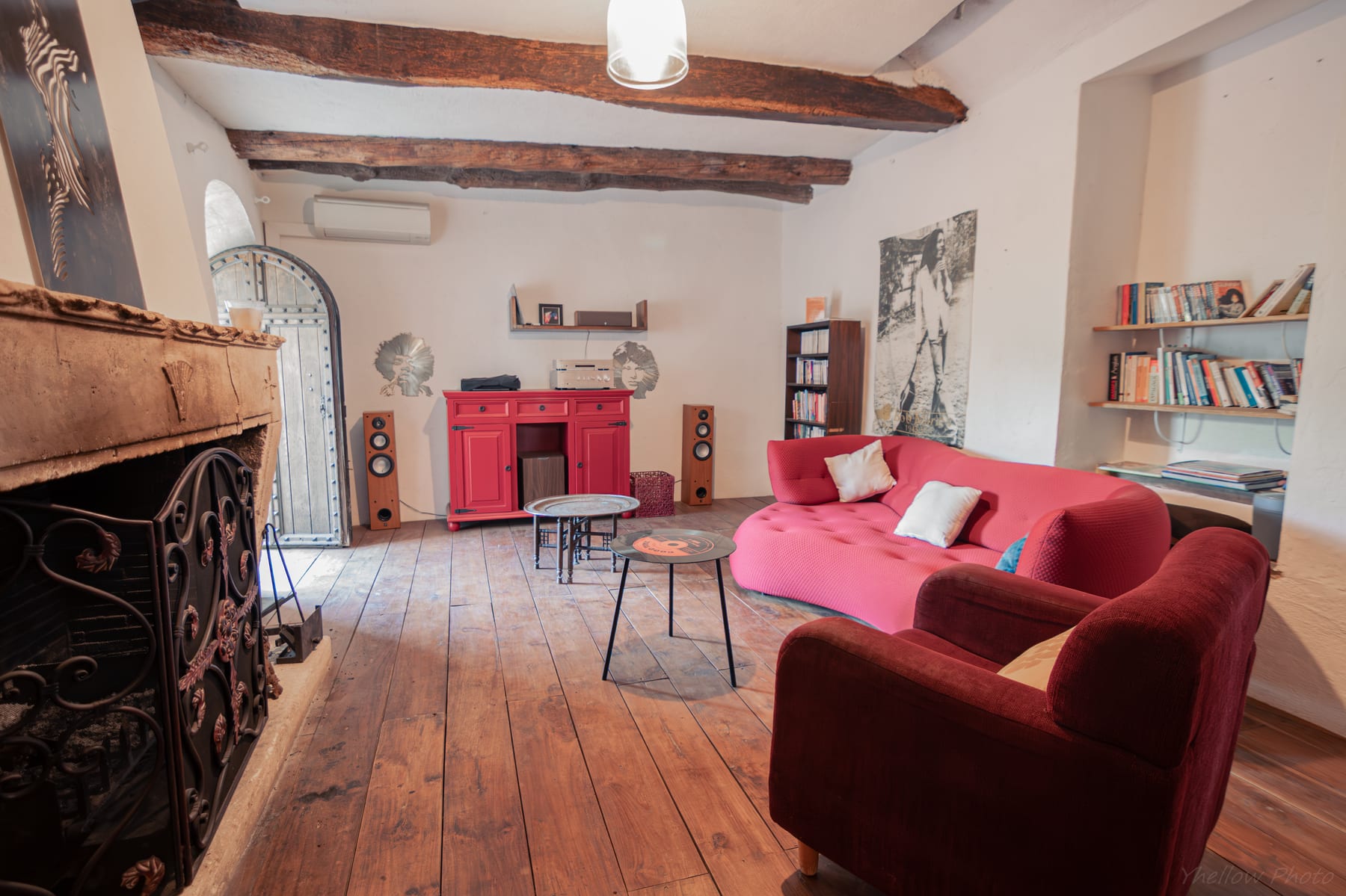 Grand salon chaleureux avec canapé, bibliothèque et poutres apparentes dans une maison d’hôtes à Esparron-de-Pallières