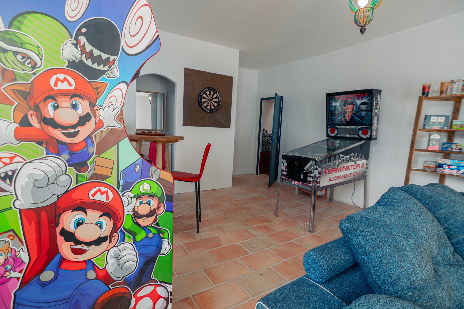 Salle de jeux avec borne d’arcade Mario, flipper et fléchettes pour les hôtes du Couvent des Pallières
